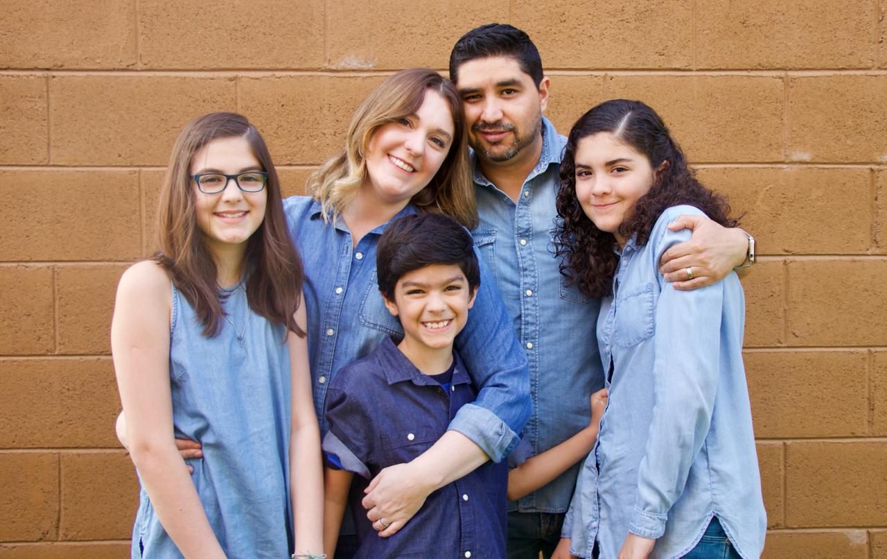 A family is posing for a picture in front of a brick wall.