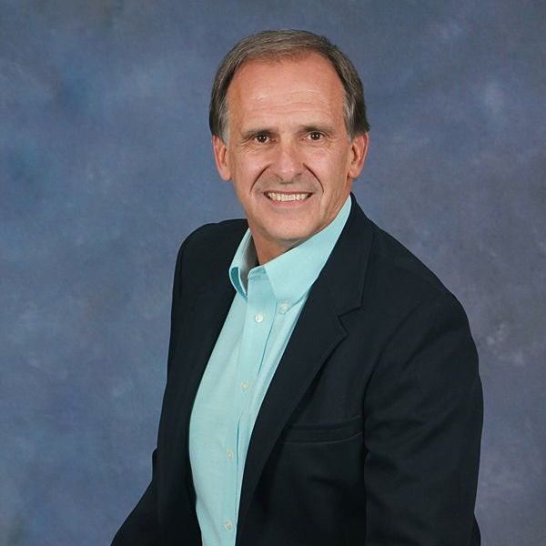 A man in a red plaid shirt is smiling for the camera.