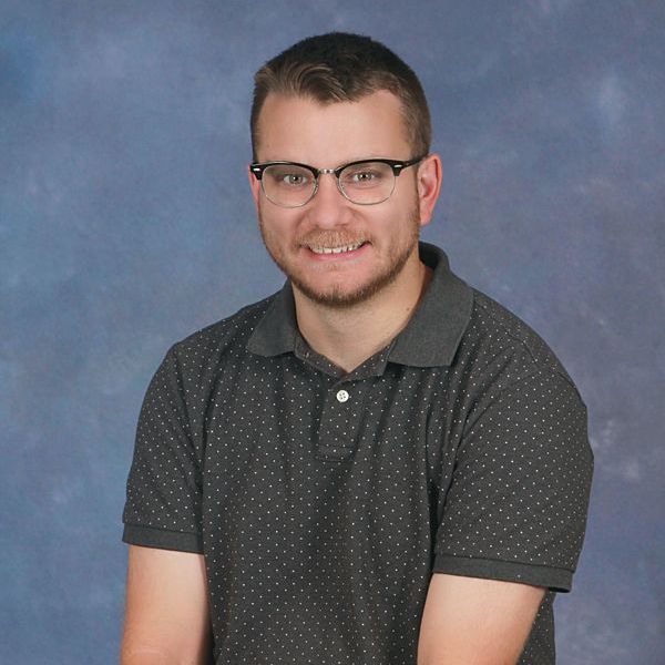 A man with glasses and a beard is wearing a white hoodie