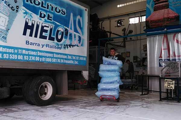 Un hombre carga bolsas de hielo en un camión.