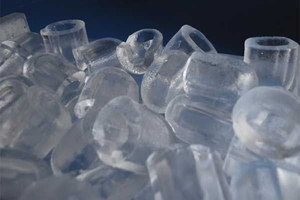 Un montón de cubitos de hielo transparentes sobre un fondo azul.