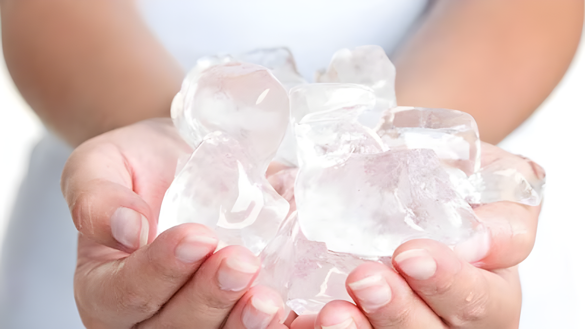 Una persona sostiene un montón de cubitos de hielo en sus manos.