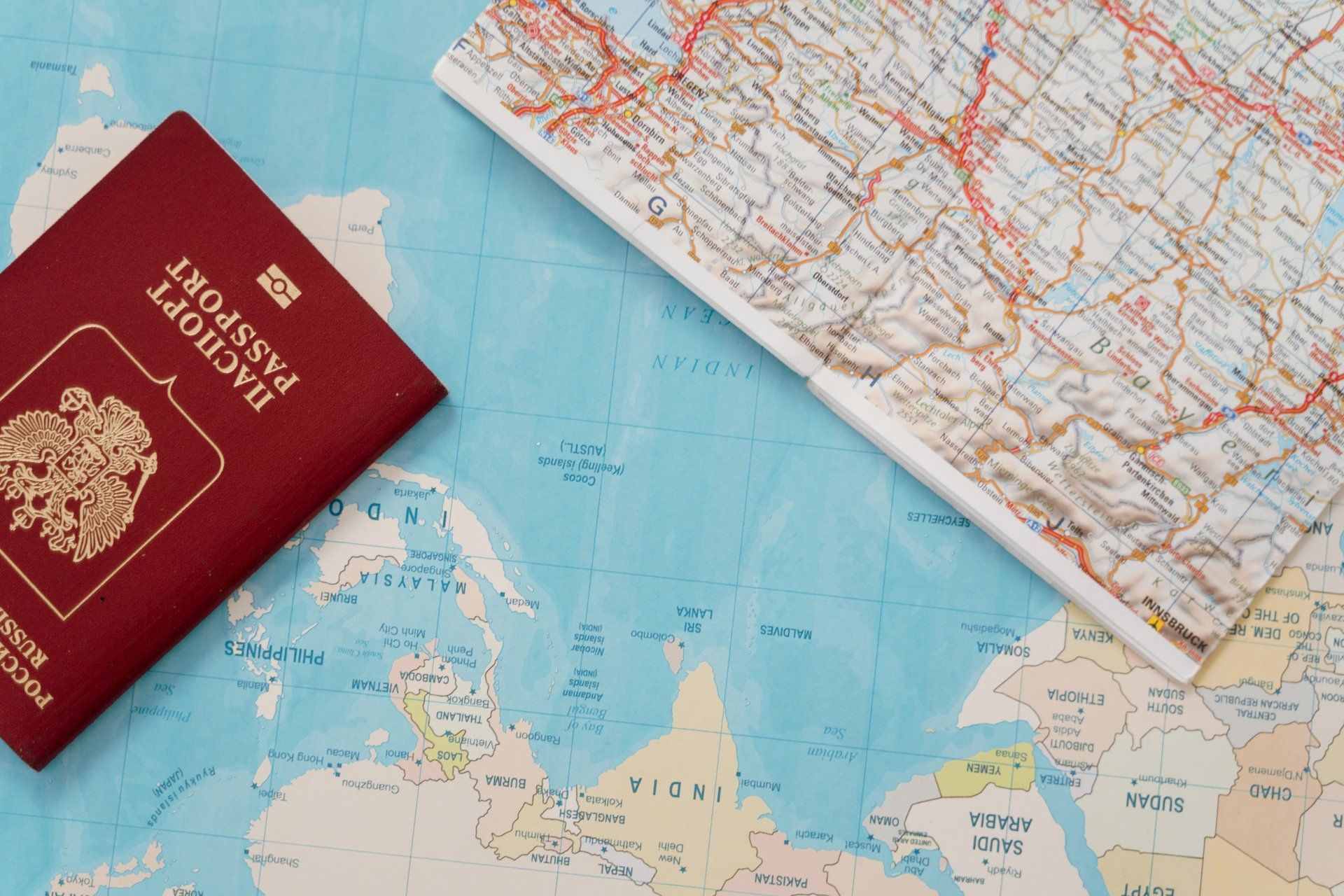 A red passport is sitting on top of a map.