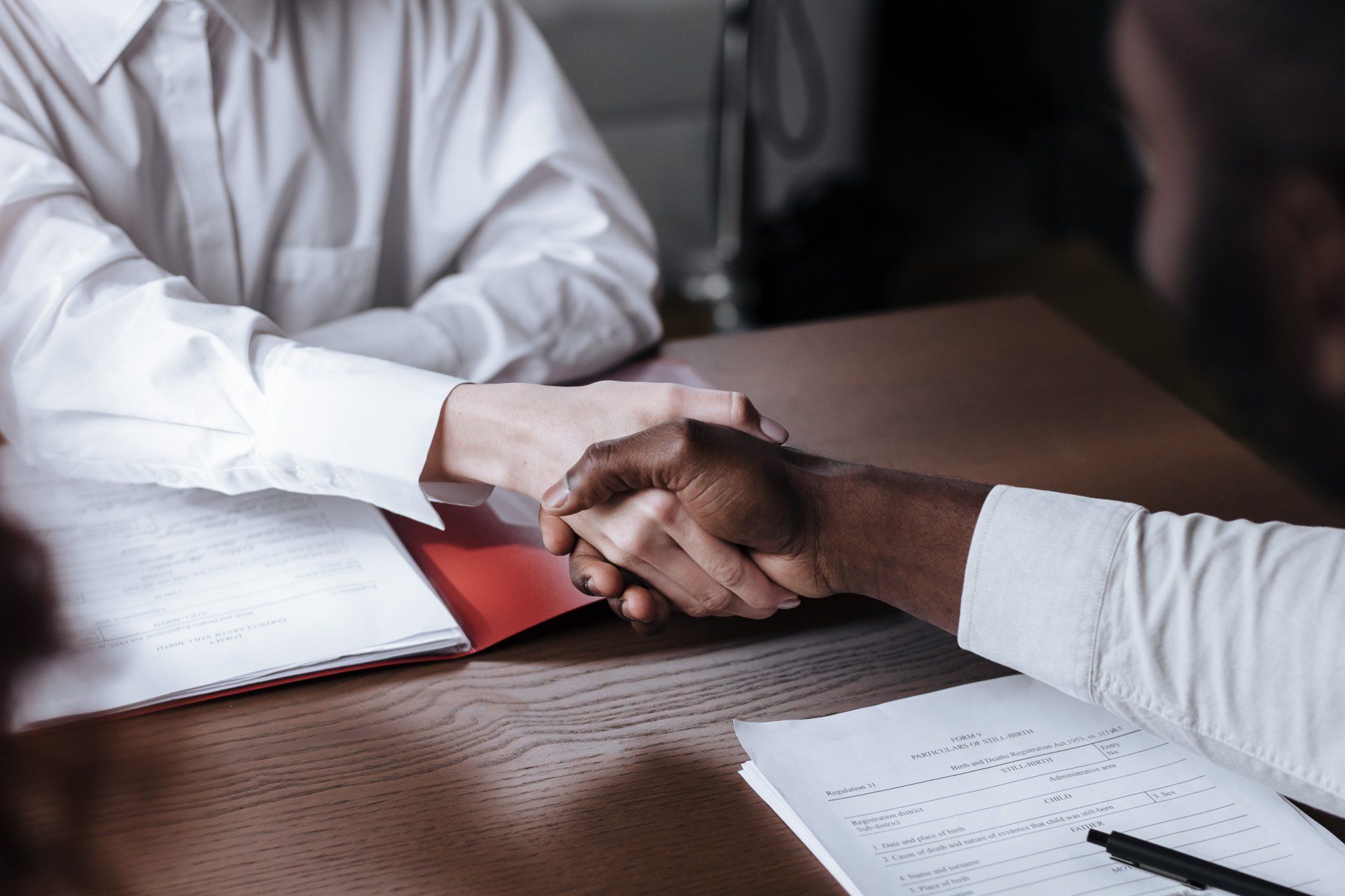 A man and a woman are shaking hands over a table.