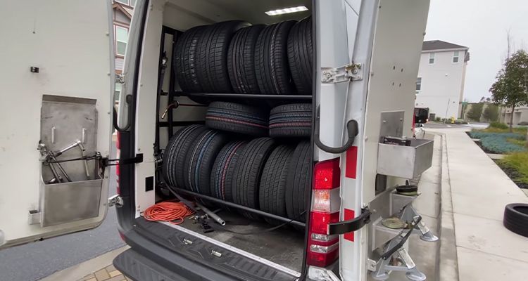 Open van interior with racks holding numerous car tires.