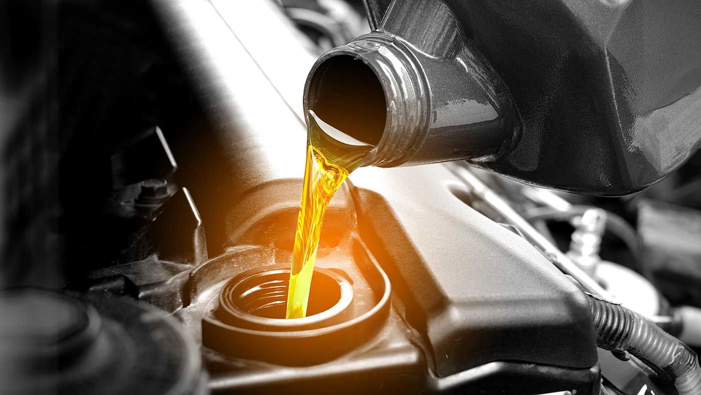 Yellow motor oil being poured into a car engine.