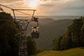 A cable car is going up a mountain at sunset.