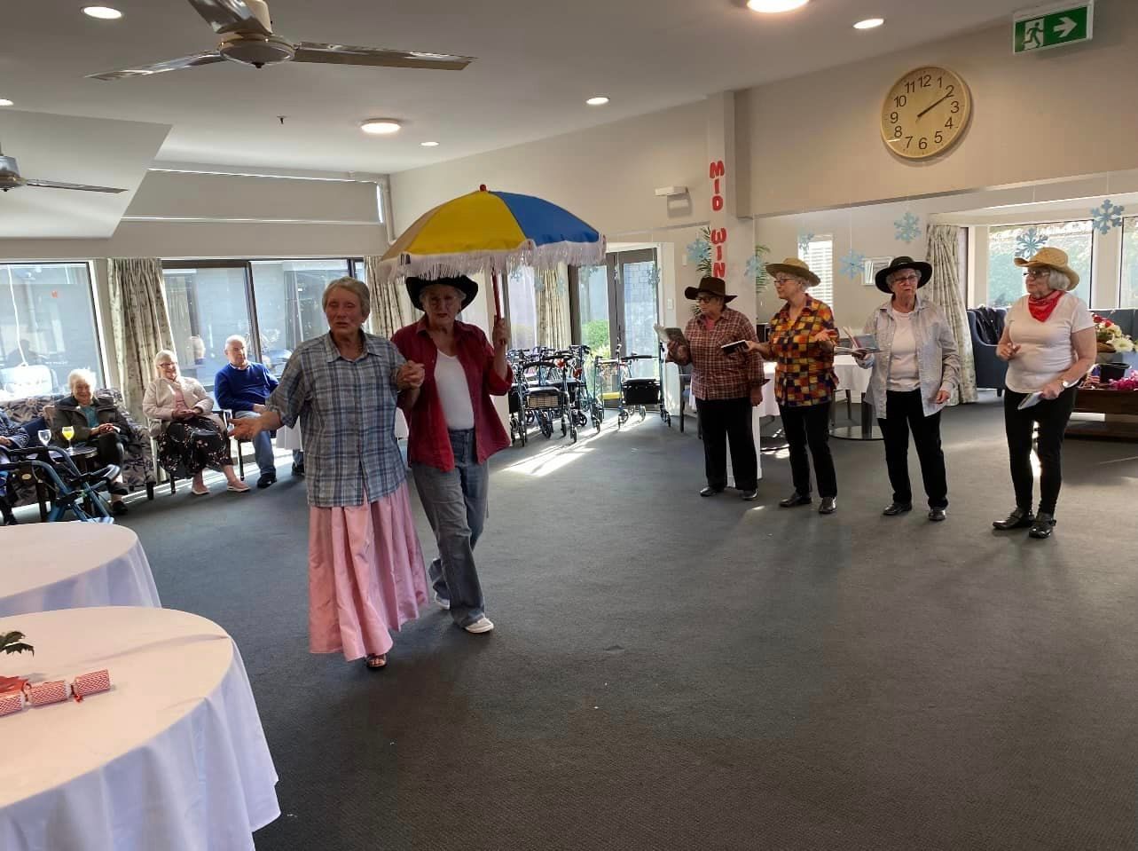 A group of people are dancing in a room with a clock on the wall.