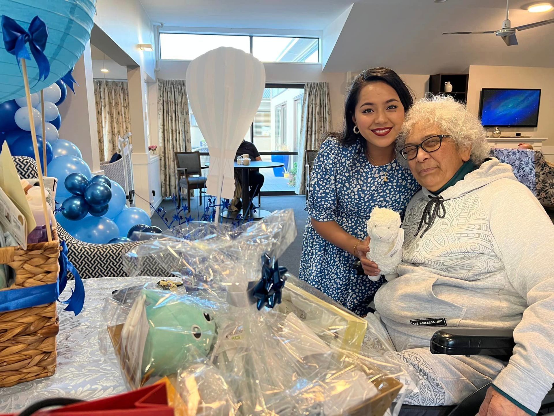 A woman is standing next to an elderly woman in a wheelchair.