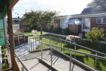 a lawn with a table and chairs and a blue umbrella