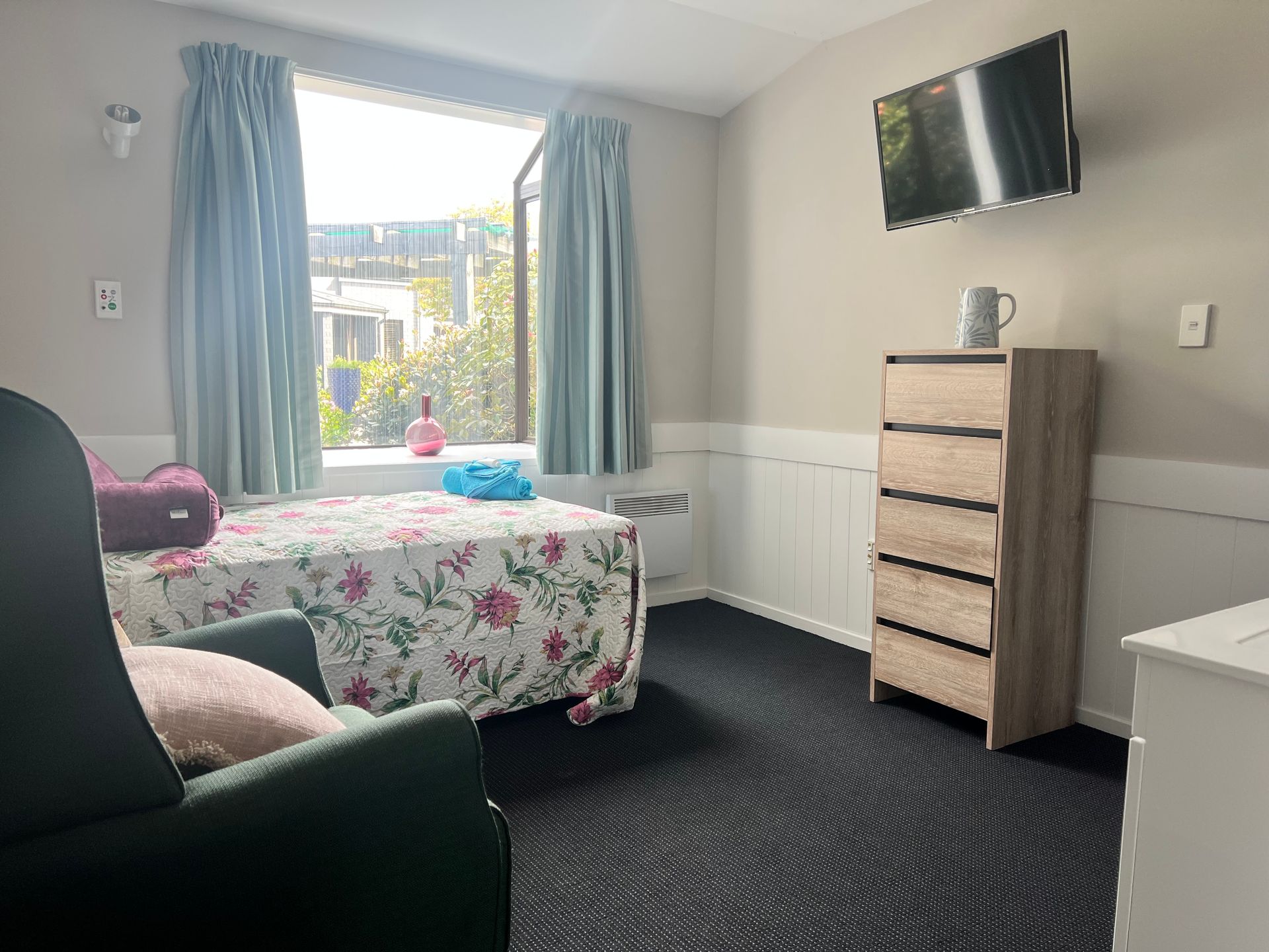 A bedroom with a bed , chair , dresser and television.