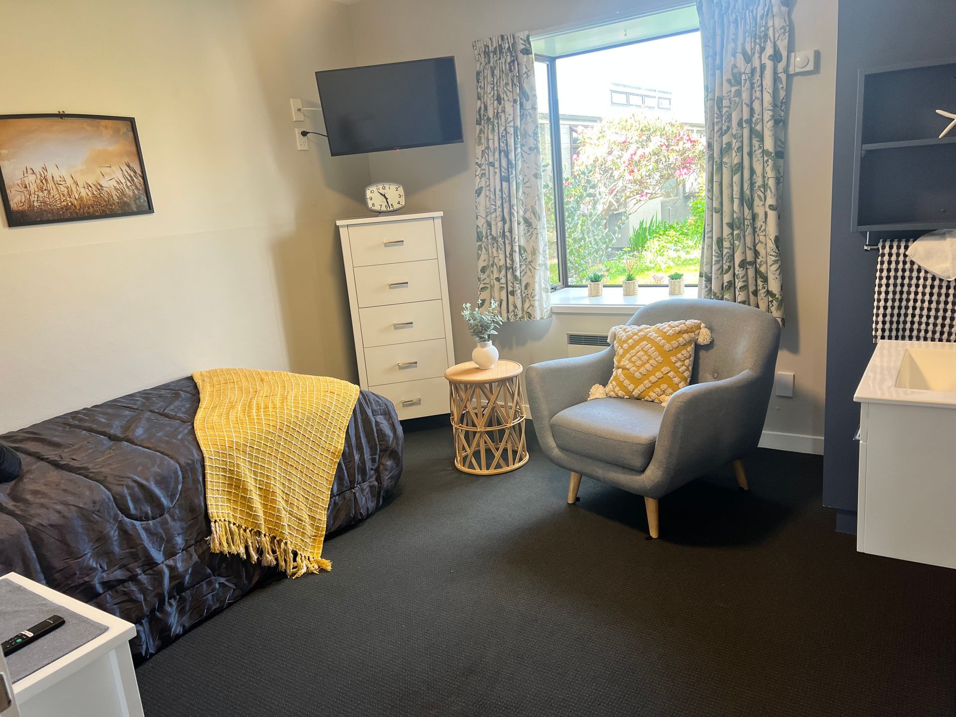 A bedroom with a bed , chair , dresser and television.