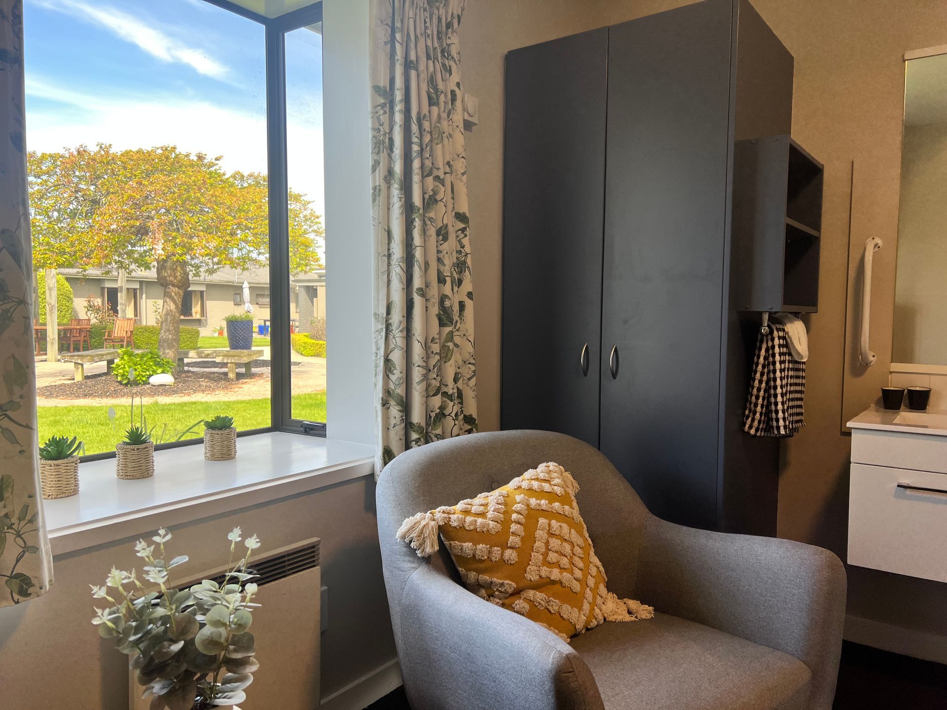 A living room with a chair , wardrobe , mirror and window.