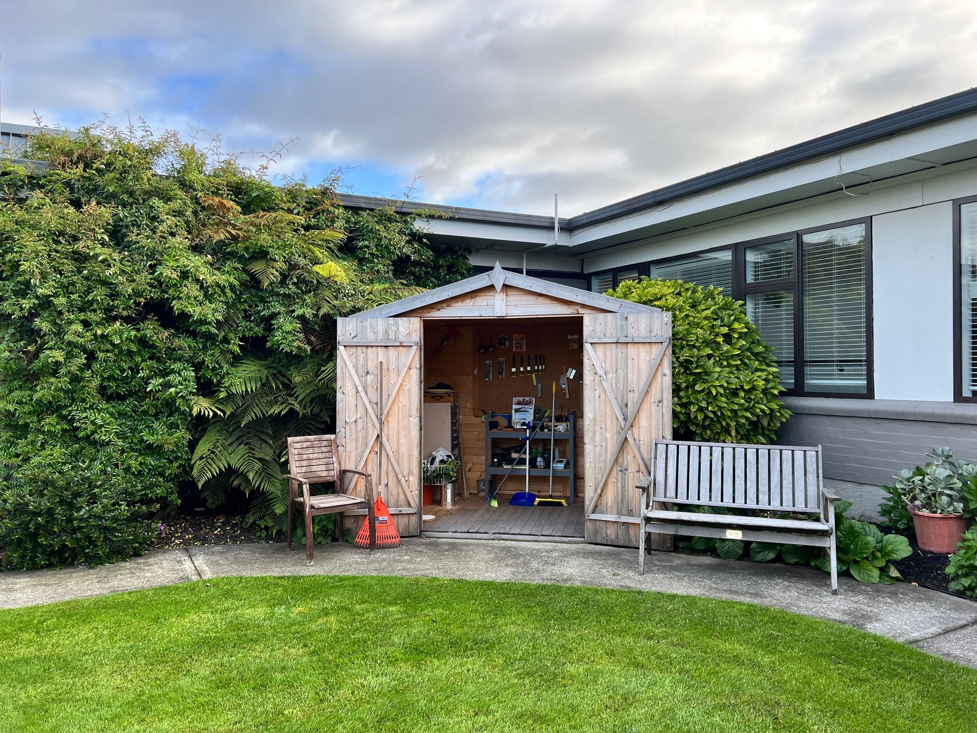 A wooden shed is sitting in the backyard of a house.