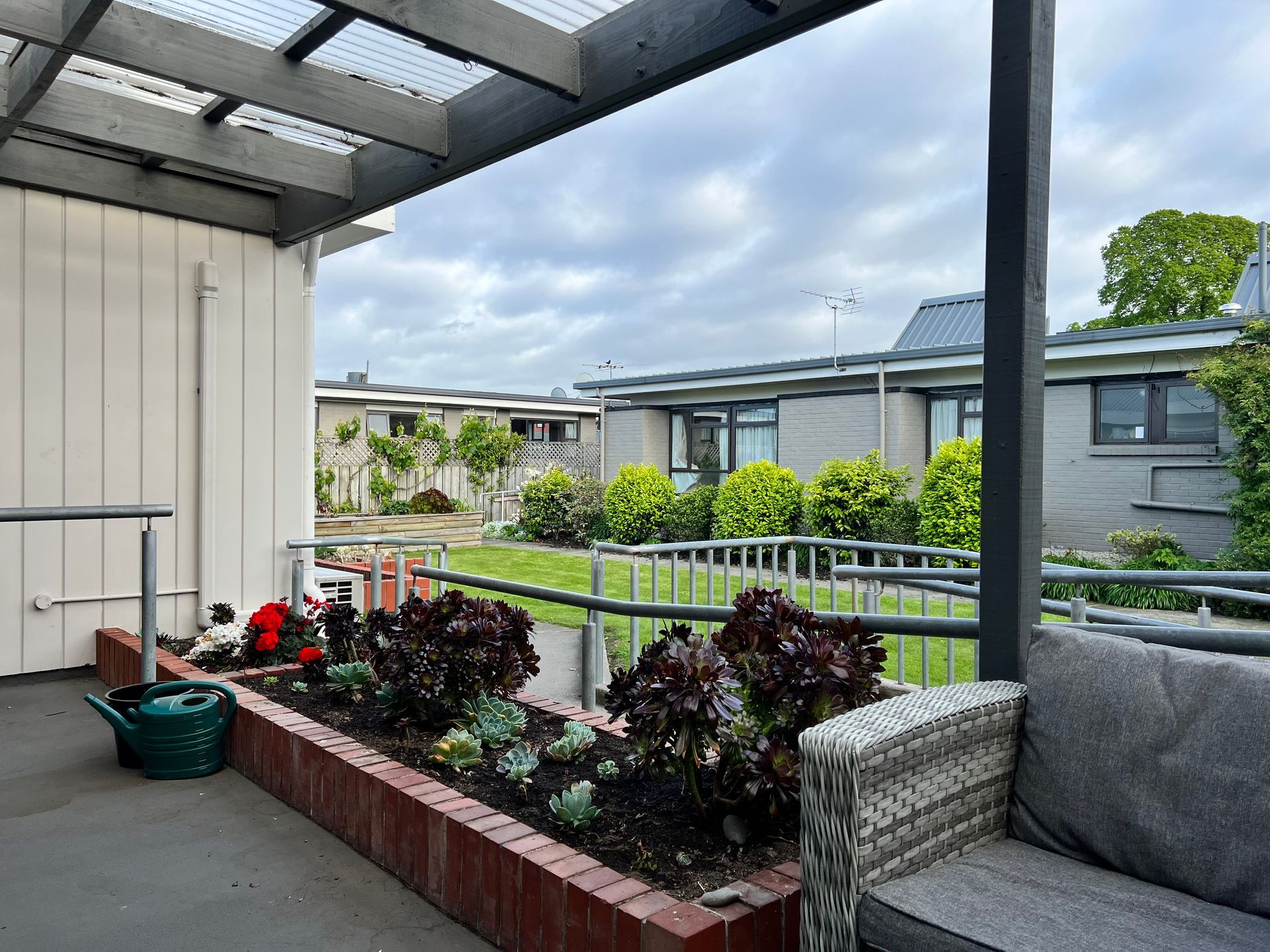 A patio with a couch and a planter with plants in it.