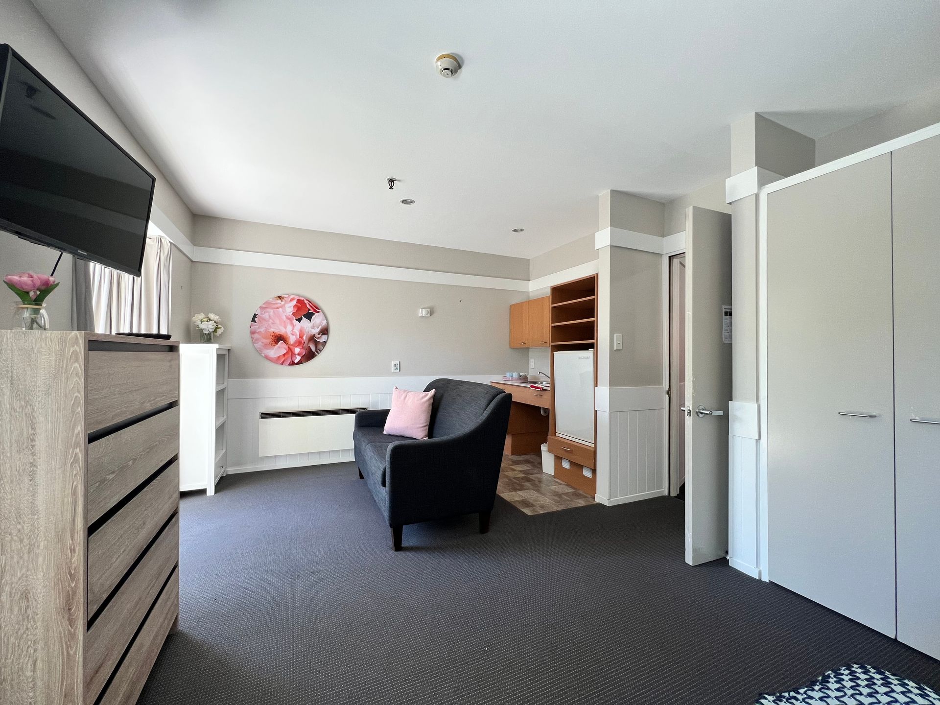 A living room with a couch , chair , television and dresser.