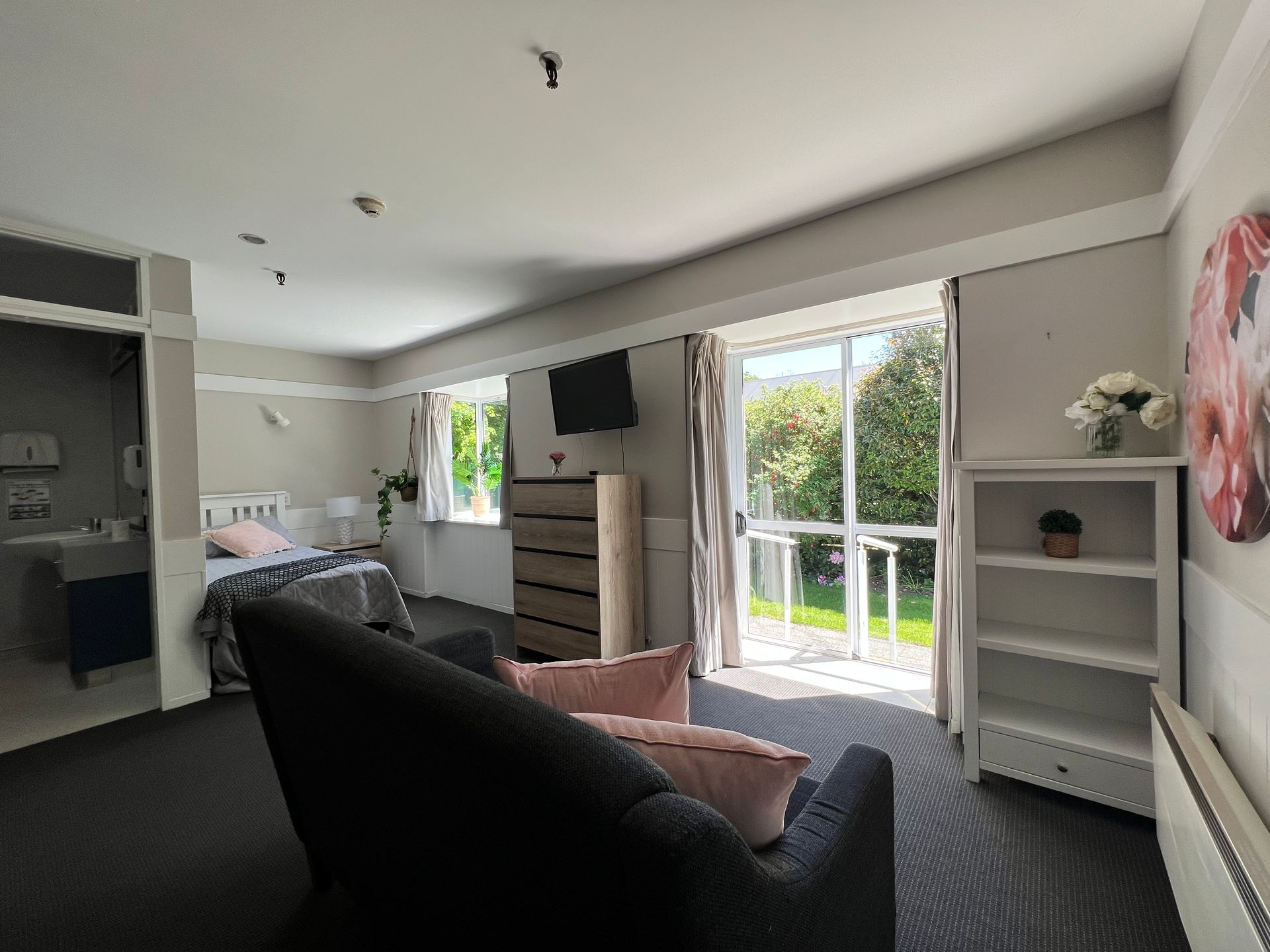 A living room with a couch , chair , dresser and television.