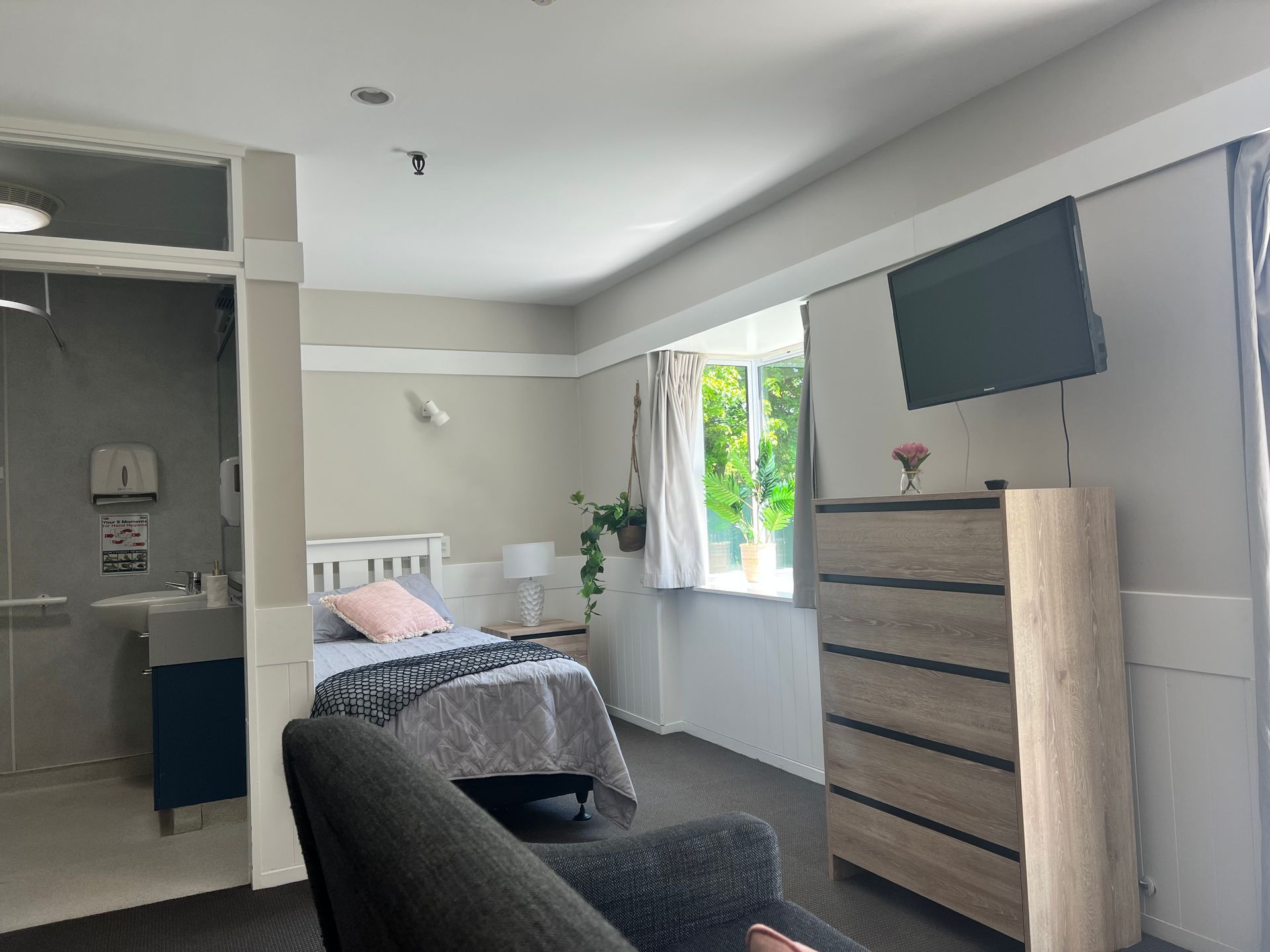 A bedroom with a bed , dresser , chair and television.