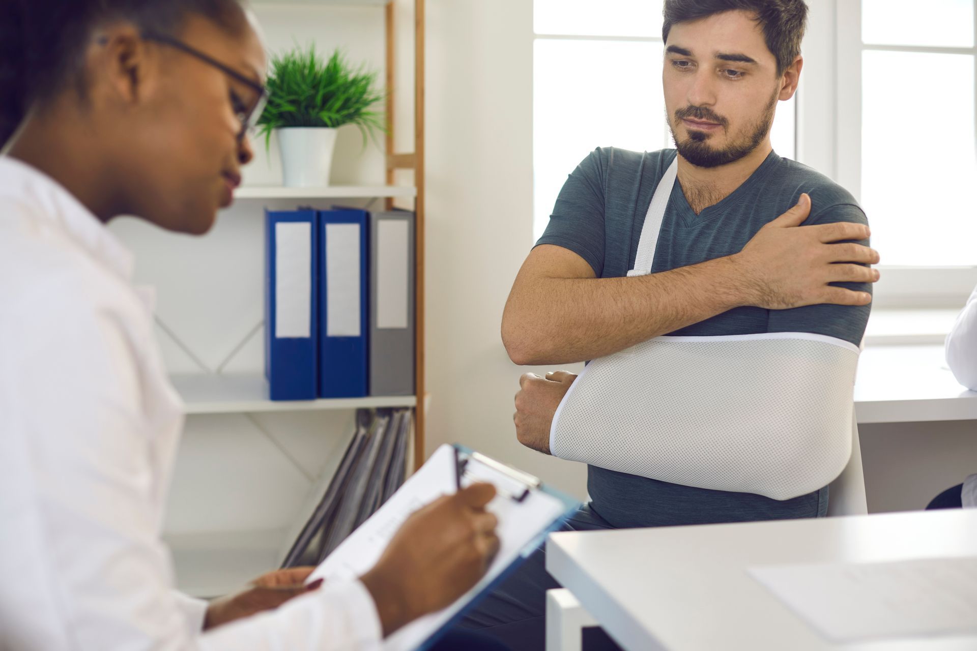 Um homem com um braço quebrado e engessado está conversando com um médico.