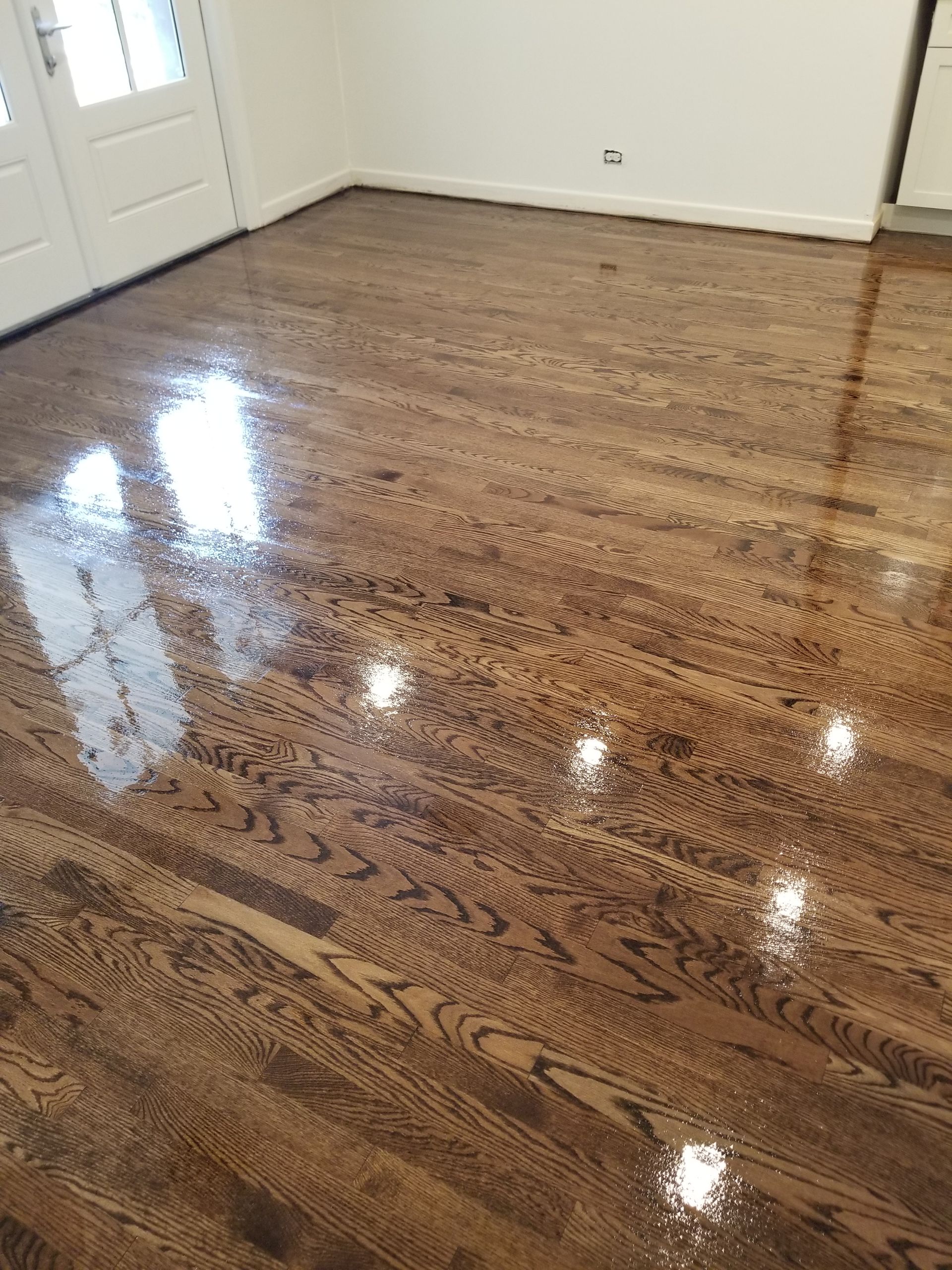 Shiny hardwood floor in an empty room with white walls and doors