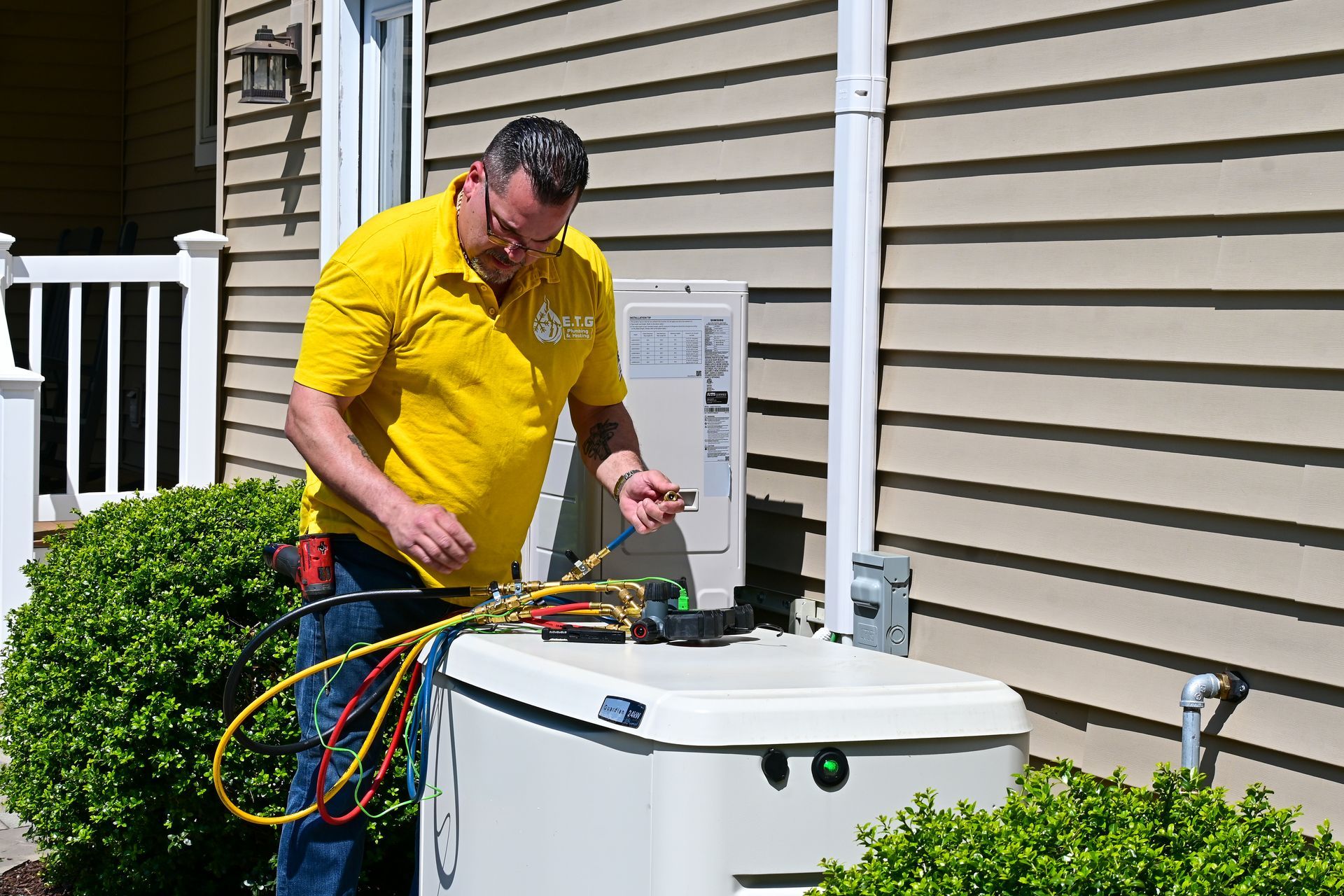 A man in a yellow shirt is working on a generator outside of a house.