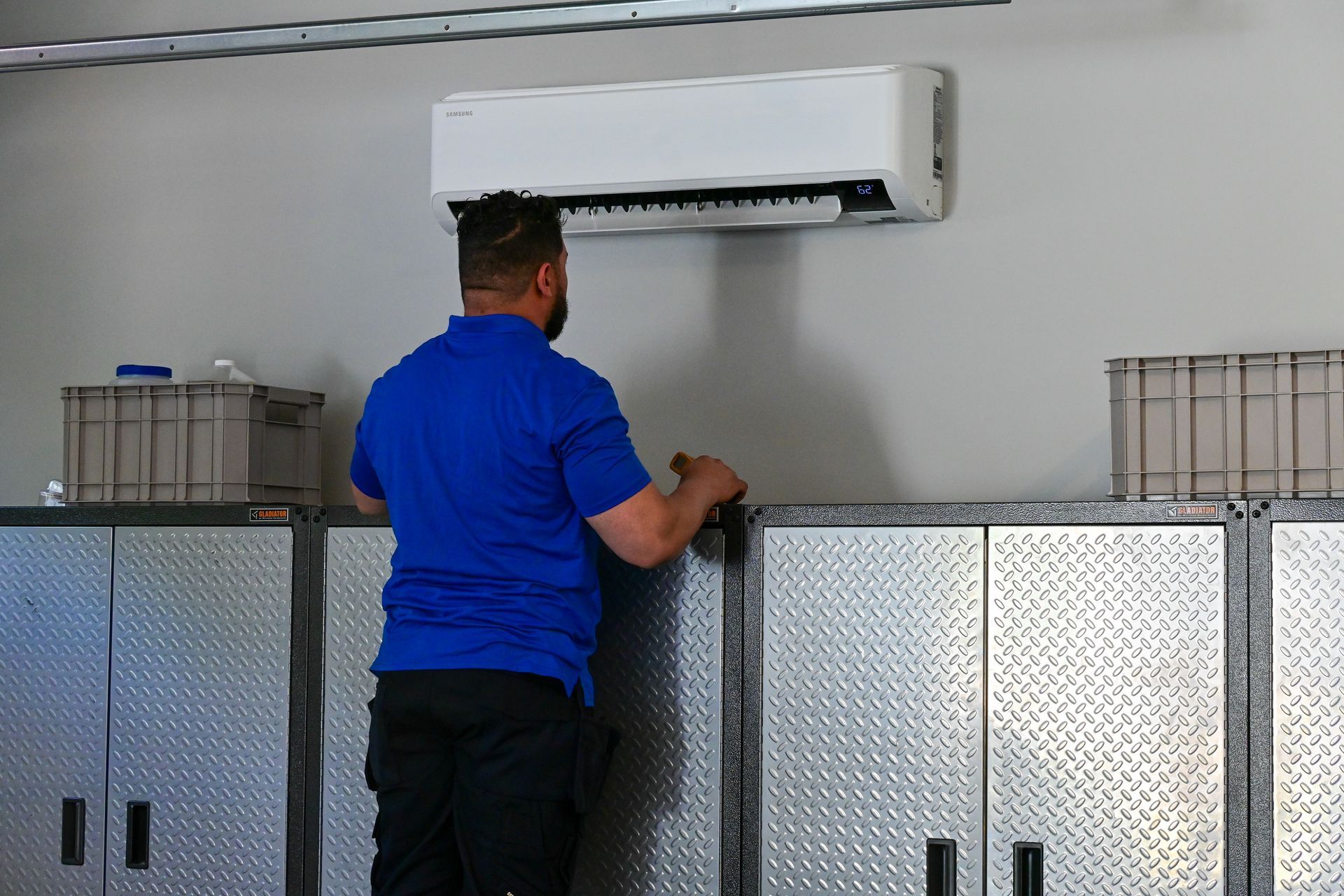 A man is installing a wall mounted air conditioner in a garage.