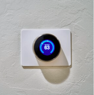 A thermostat on a wall that says 63 degrees