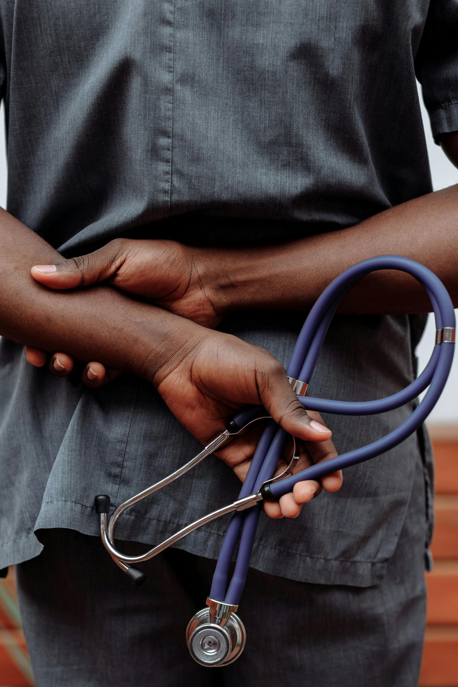 A close up of a person holding a stethoscope behind their back.