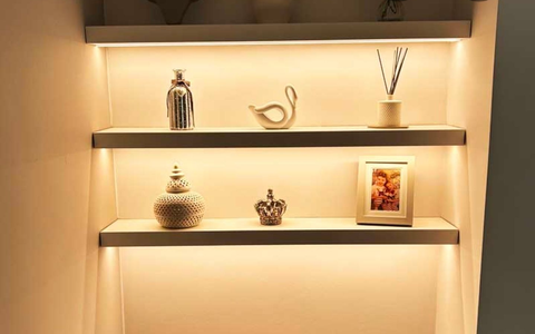 Built-in shelves with warm lighting showcasing decorative items: vases, swan, photo frame.