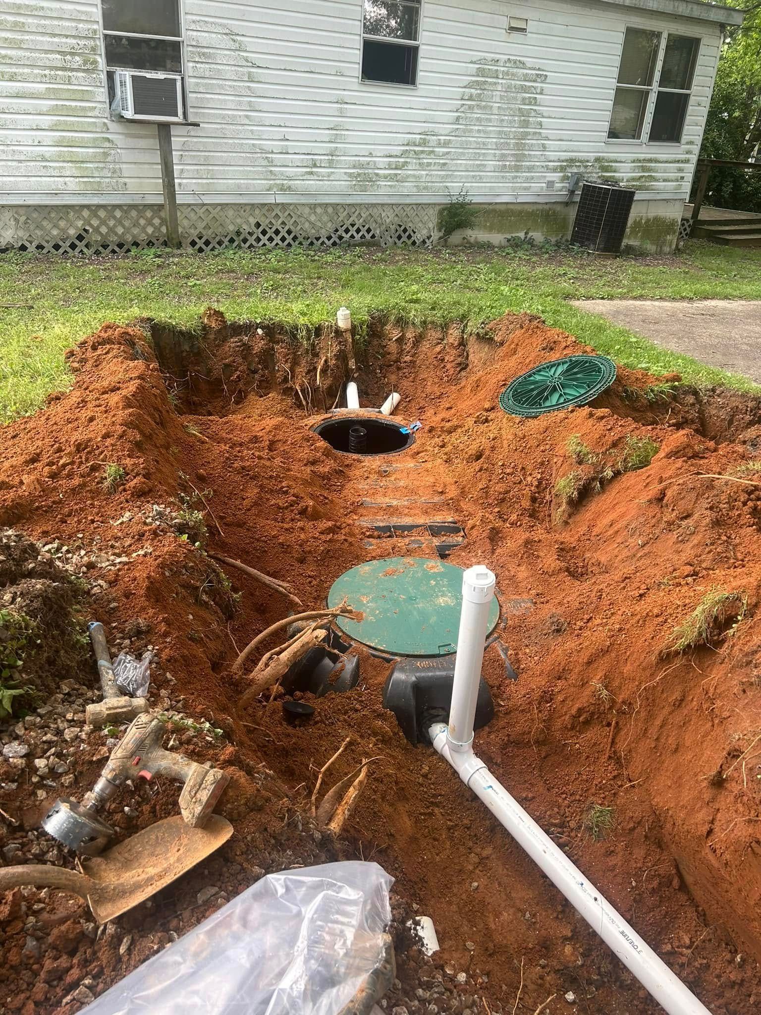 Septic tank installation in a residential yard; brown soil surrounds exposed components.