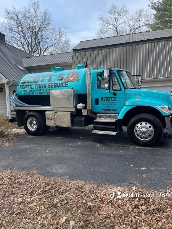 A teal septic tank service truck parked in a driveway. The truck has the company name 