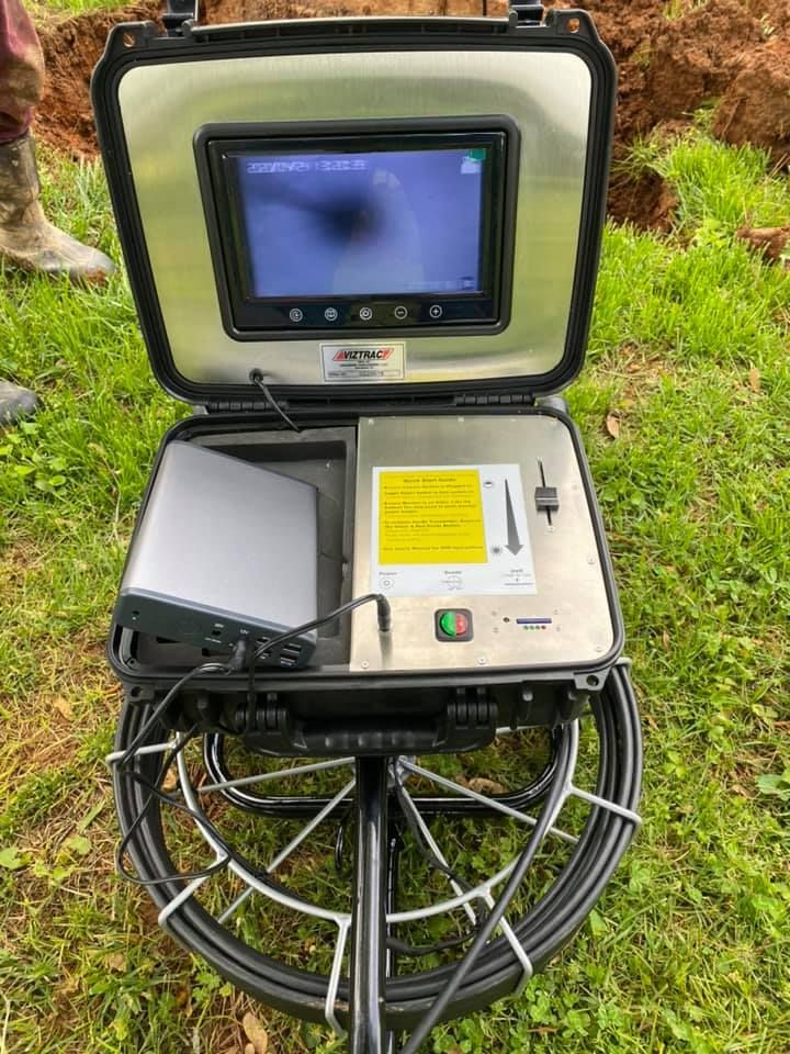 Gray industrial air compressor on wheels in a brick-walled room.