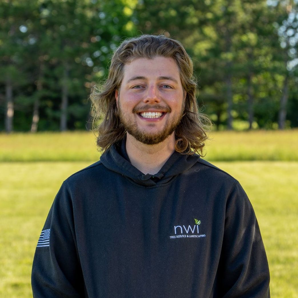 A man with long hair and a beard is wearing a black hoodie and smiling.