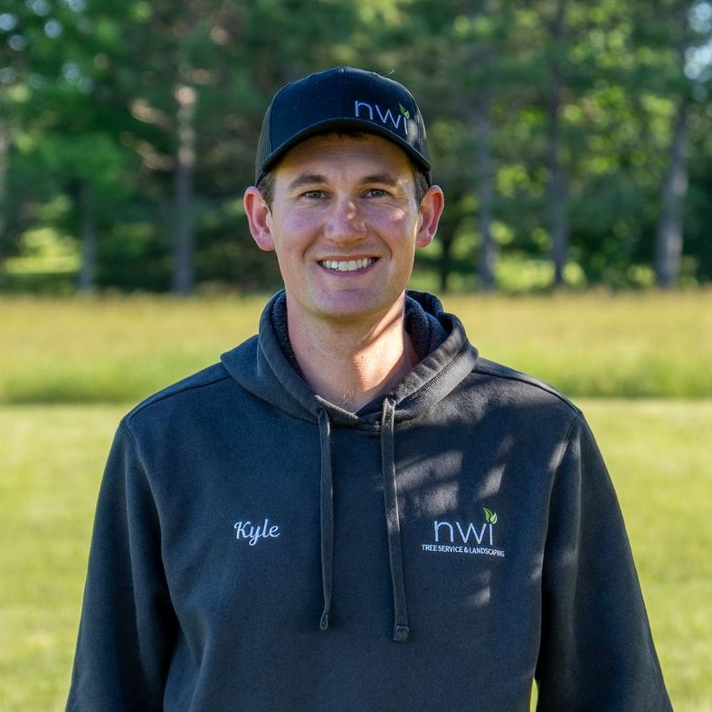 A man wearing a black hoodie and a black hat is smiling for the camera.