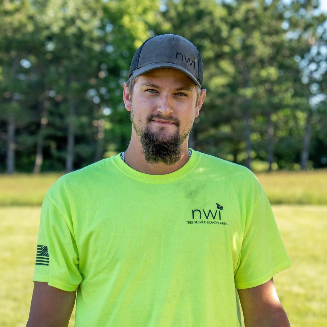 A man with a beard is wearing a yellow t-shirt and a hat.