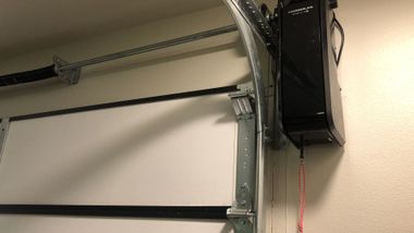 Garage ceiling with an open garage door track and a black wall-mounted opener unit.