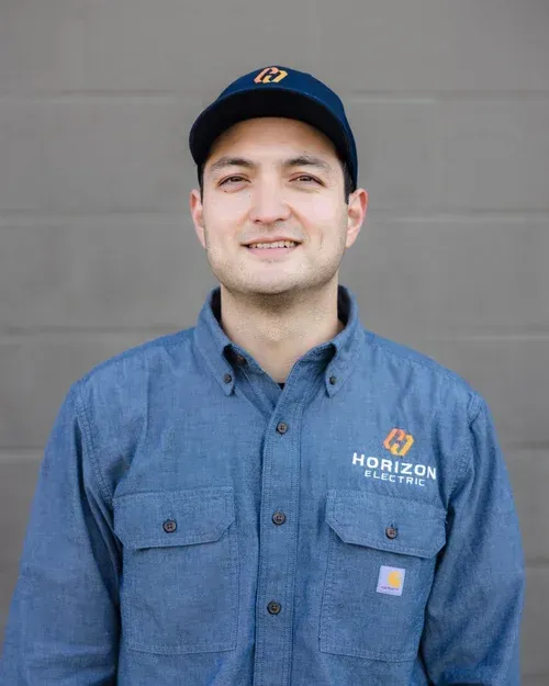 A person in a blue work shirt and cap with a 