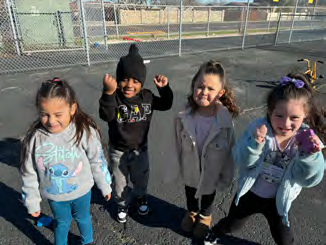 A group of young children are standing next to each other in a parking lot.