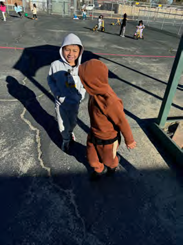 Two children in costumes are standing next to each other in a playground.