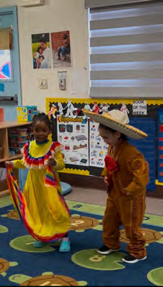 A boy and a girl in mexican costumes are dancing in a classroom.