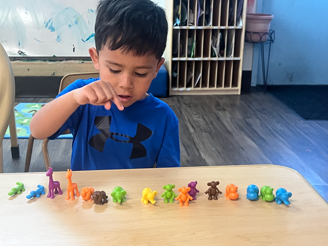 A young boy is sitting at a table playing with toys.