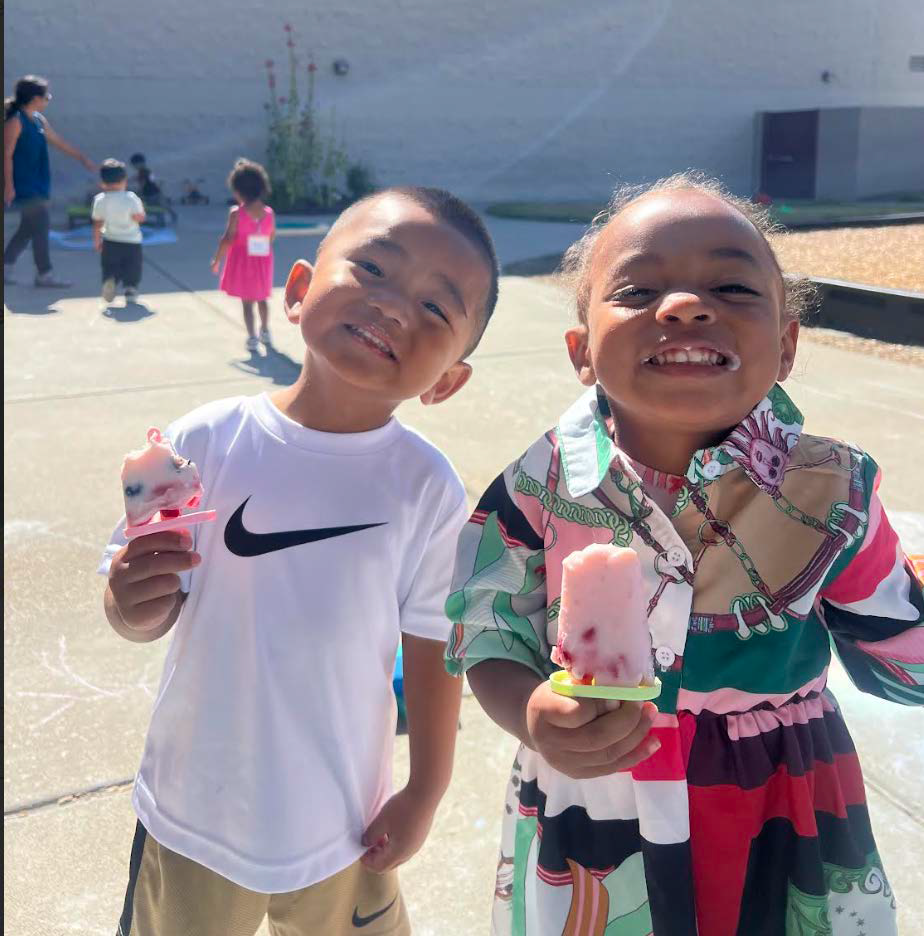 A boy and a girl are holding popsicles and smiling for the camera
