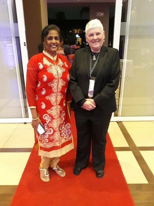 Two women standing next to each other on a red carpet