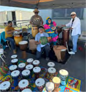 A group of people are playing drums and a man is holding a watermelon.