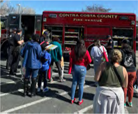 A group of people are gathered under a purple tent.