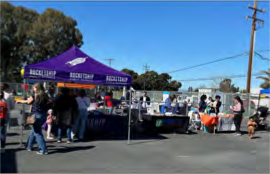 A group of people are gathered under a purple tent.