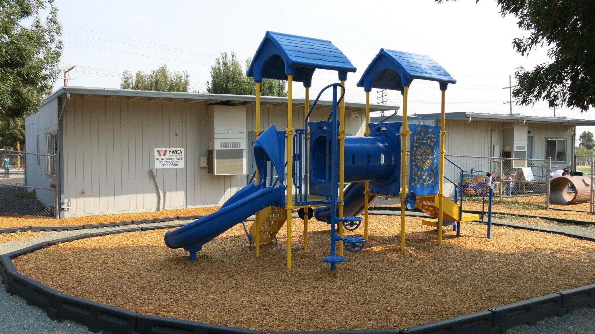 A blue and yellow playground set in front of a building