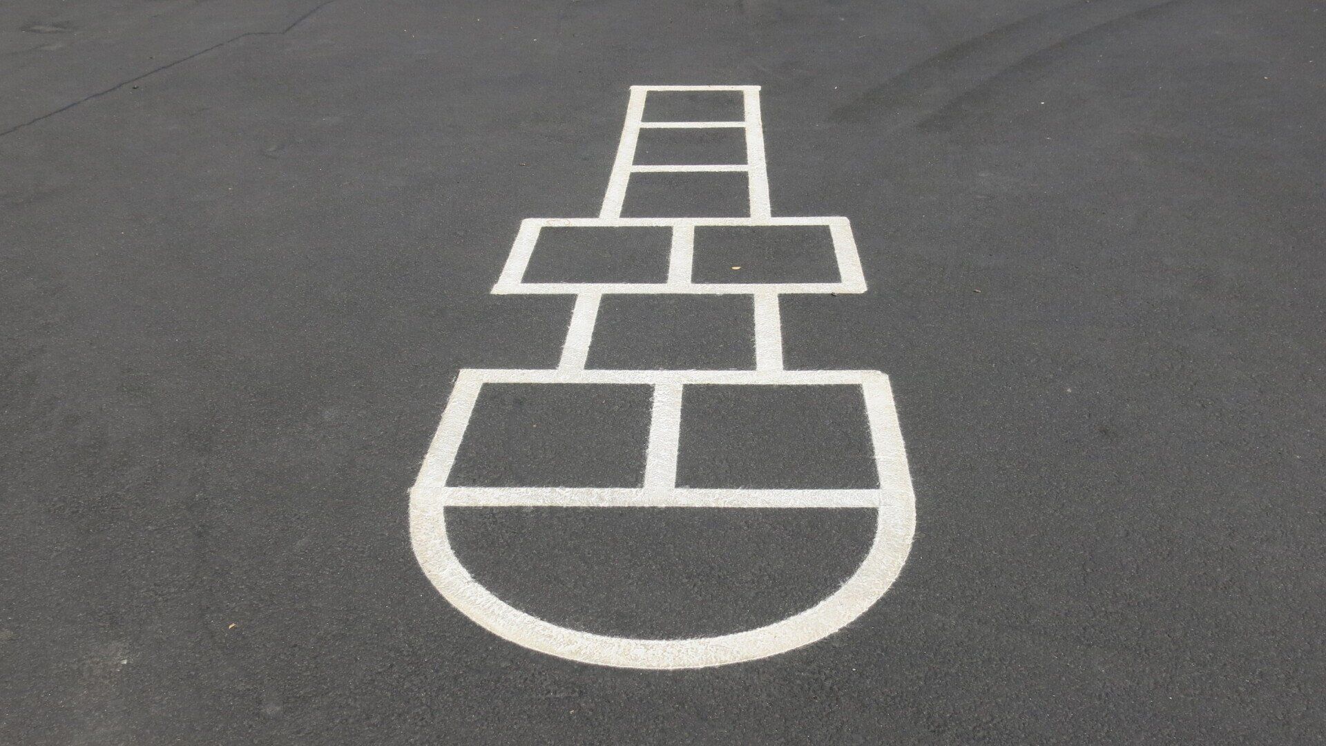 A hopscotch pattern is painted on the asphalt.