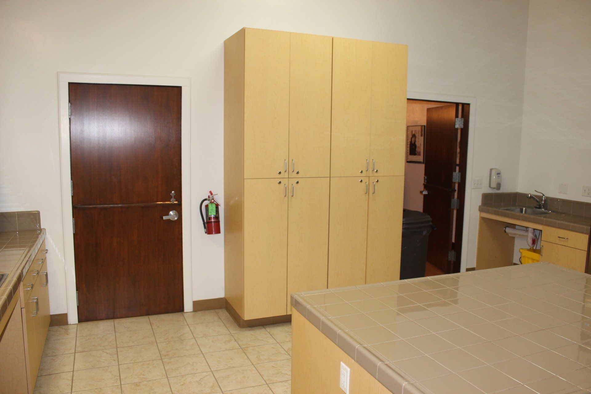 A kitchen with lots of cabinets and a fire extinguisher on the wall