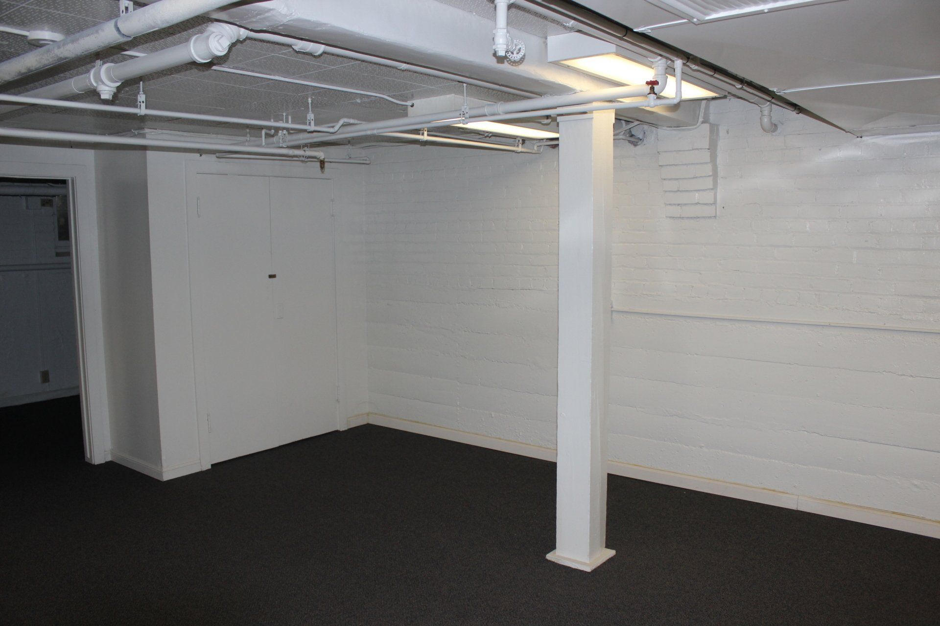 An empty basement with white walls and black carpet